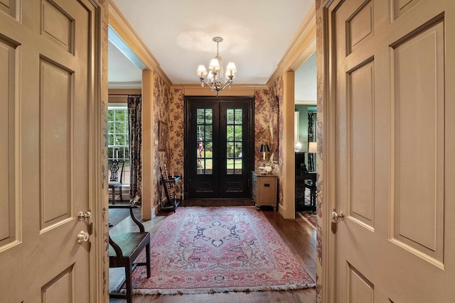 entryway with french doors, crown molding, an inviting chandelier, and wood finished floors