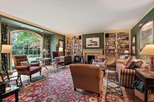 living room with crown molding, a fireplace, built in shelves, and wood finished floors