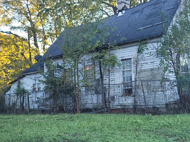 view of home's exterior featuring a shingled roof and a lawn