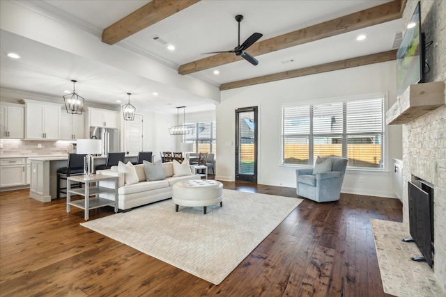 living room featuring baseboards, dark wood-style flooring, beamed ceiling, a fireplace, and ceiling fan with notable chandelier