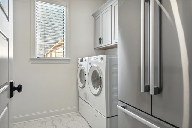 laundry room with marble finish floor, washing machine and clothes dryer, cabinet space, and baseboards