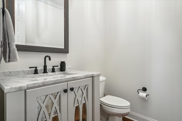 bathroom with vanity, toilet, and baseboards