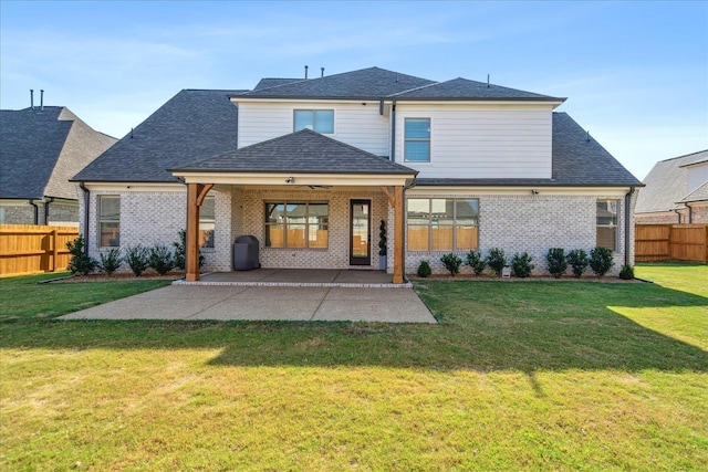 rear view of house featuring a yard, brick siding, a patio area, and fence