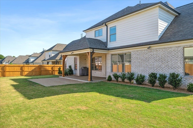 rear view of property featuring a yard, a patio area, fence, and brick siding