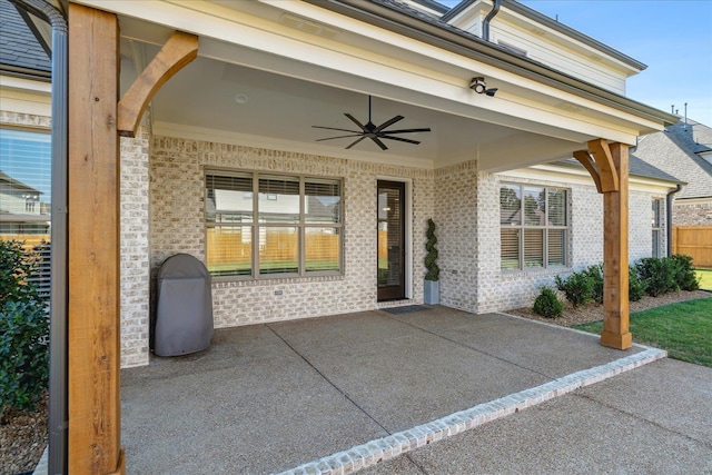 doorway to property with brick siding, a patio area, and a ceiling fan