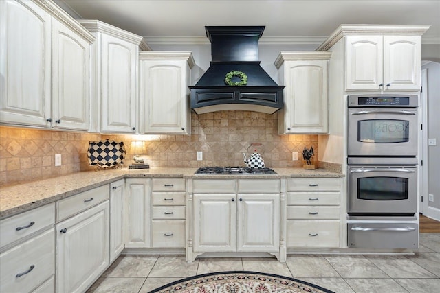 kitchen with stainless steel appliances, custom range hood, light stone countertops, a warming drawer, and crown molding