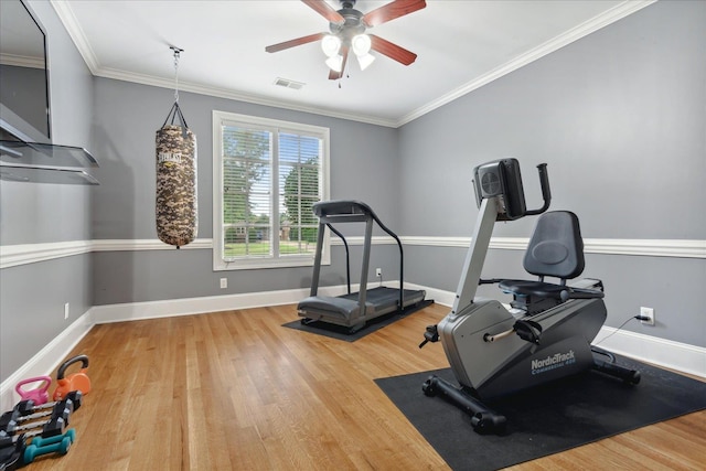 workout area featuring visible vents, crown molding, baseboards, and wood finished floors