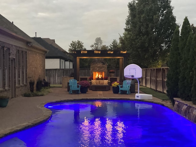 view of pool with a patio, an outdoor stone fireplace, fence, and a fenced in pool