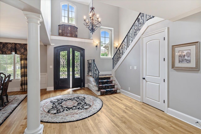 foyer entrance with ornate columns, plenty of natural light, and wood finished floors