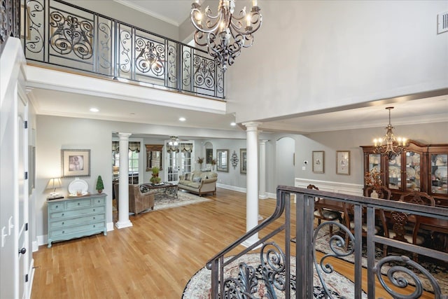 entryway featuring visible vents, light wood-style floors, ornamental molding, ornate columns, and a notable chandelier