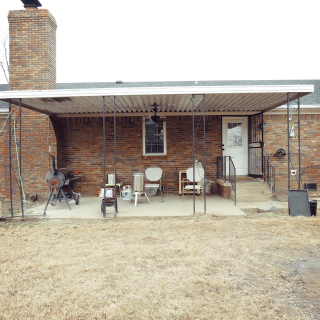 back of property with a chimney, a patio, and brick siding