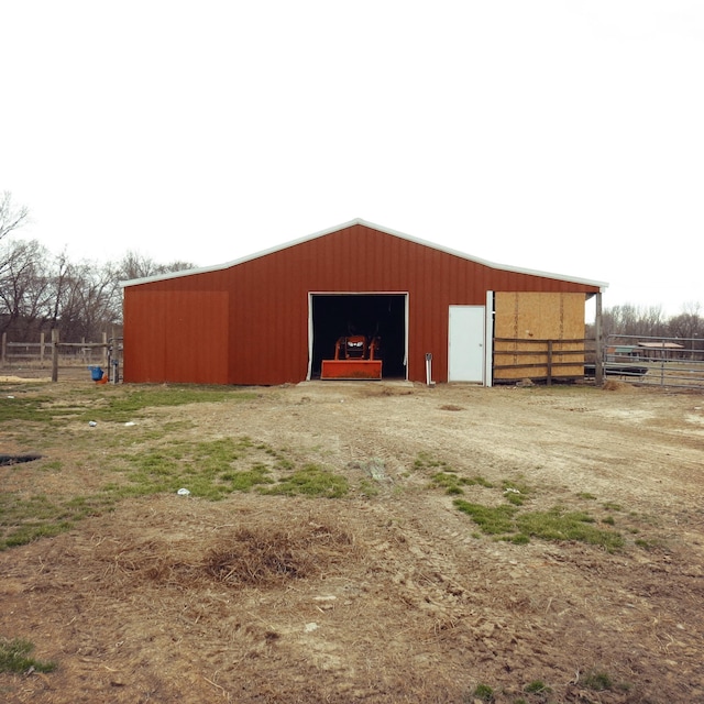 view of pole building with driveway and fence