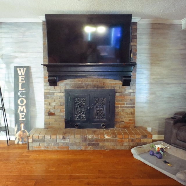 room details with a textured ceiling, ornamental molding, a brick fireplace, and wood finished floors