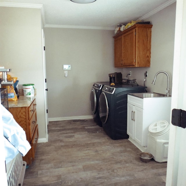 laundry room featuring light wood-style flooring, crown molding, a sink, and independent washer and dryer