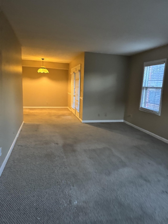 empty room featuring carpet and baseboards