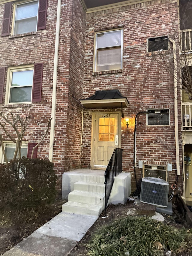 view of front facade with cooling unit and brick siding