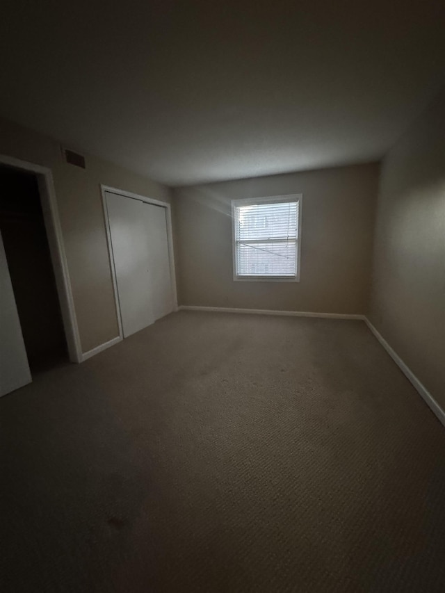 unfurnished bedroom with a closet, carpet, visible vents, and baseboards