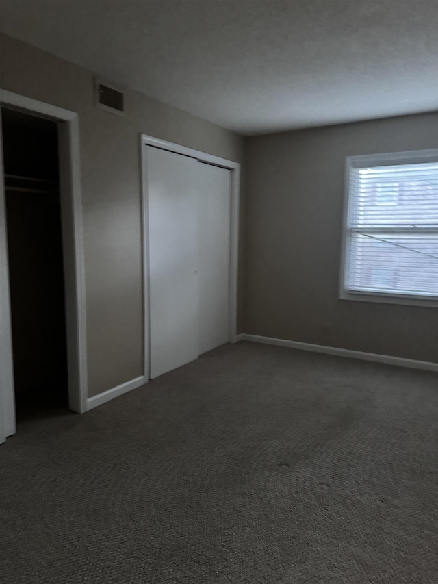 unfurnished bedroom featuring carpet floors, visible vents, and baseboards