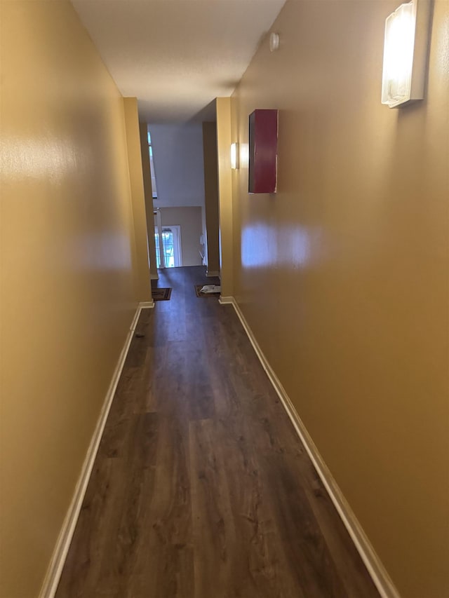 corridor with dark wood-style floors and baseboards