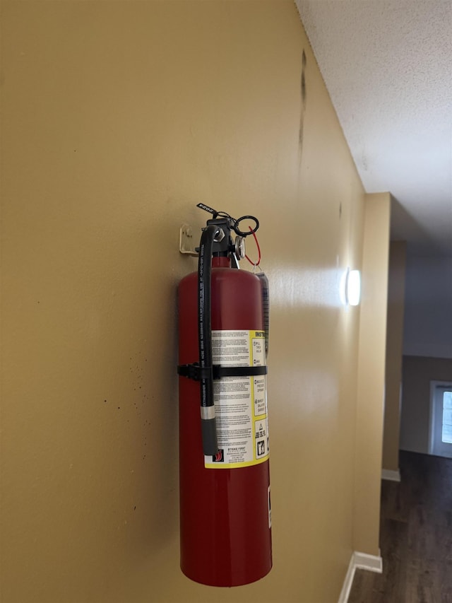 details featuring baseboards, a fire extinguisher, a textured ceiling, and wood finished floors