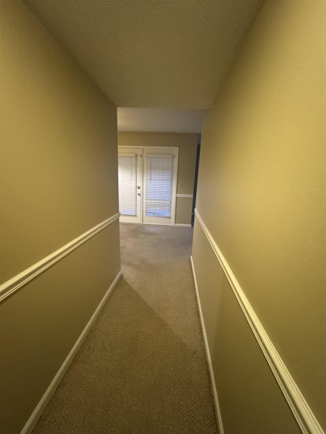 corridor with french doors, carpet flooring, and baseboards