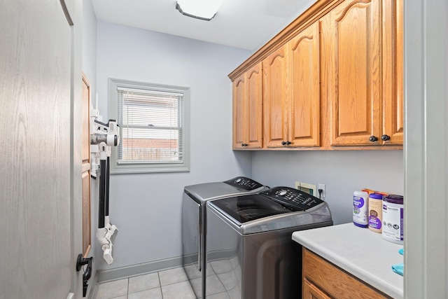 laundry room featuring light tile patterned floors, washing machine and dryer, cabinet space, and baseboards