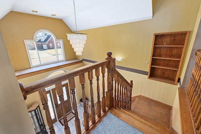 staircase with lofted ceiling, tile patterned flooring, and a notable chandelier