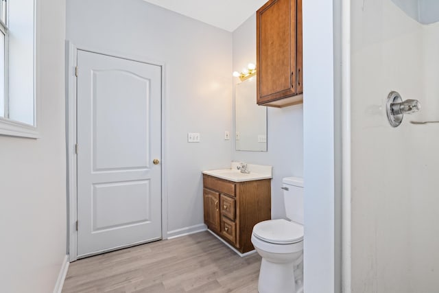 bathroom with wood finished floors, vanity, toilet, and baseboards