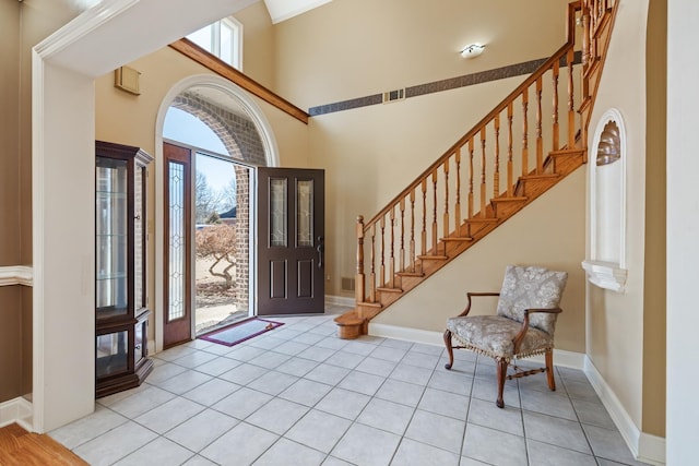 entrance foyer with a healthy amount of sunlight, a towering ceiling, and light tile patterned floors