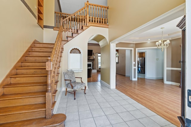 entryway featuring stairs, light tile patterned flooring, a chandelier, and crown molding