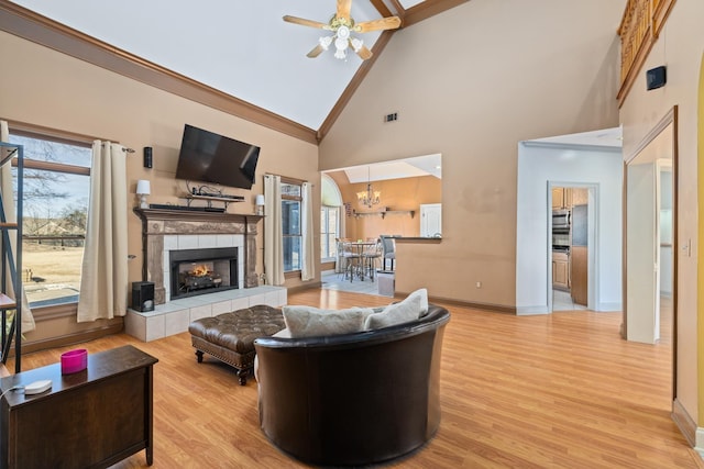 living room featuring light wood finished floors, visible vents, baseboards, a fireplace, and ceiling fan with notable chandelier