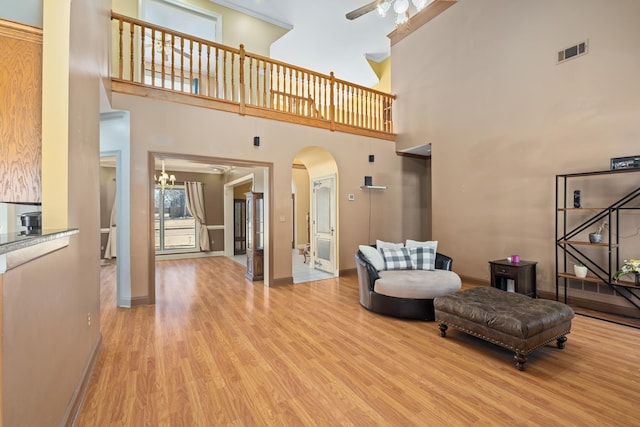 interior space with arched walkways, ceiling fan, light wood-type flooring, and visible vents