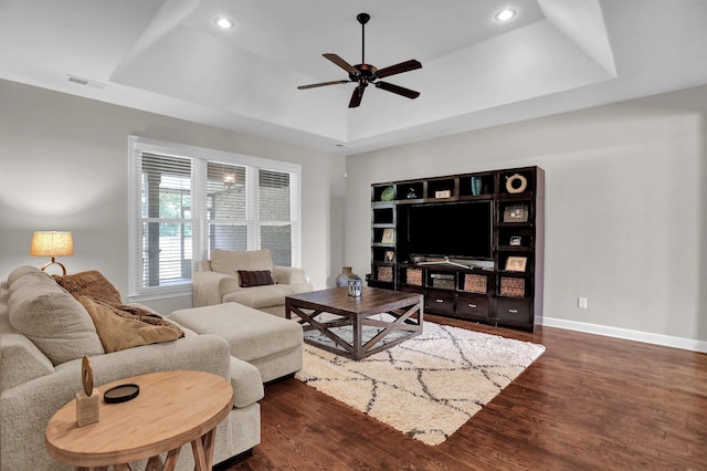 living area featuring baseboards, visible vents, a raised ceiling, dark wood-type flooring, and recessed lighting