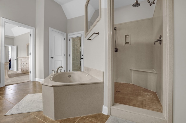 bathroom featuring tile patterned floors, vaulted ceiling, a bath, and a walk in shower