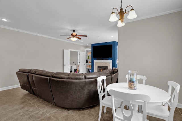 living room with crown molding, recessed lighting, a tile fireplace, baseboards, and ceiling fan with notable chandelier