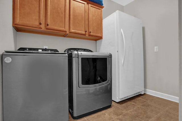 clothes washing area with cabinet space, baseboards, washer and dryer, and light tile patterned flooring