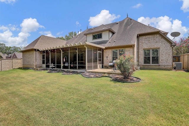 back of property featuring central AC unit, a sunroom, a fenced backyard, a yard, and brick siding