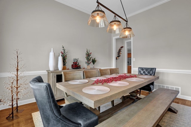 dining area featuring ornamental molding, wood finished floors, visible vents, and baseboards