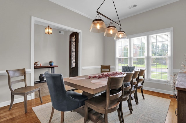 dining space featuring baseboards, visible vents, ornamental molding, and wood finished floors