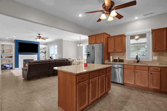 kitchen with visible vents, a tiled fireplace, a kitchen island, appliances with stainless steel finishes, and a sink