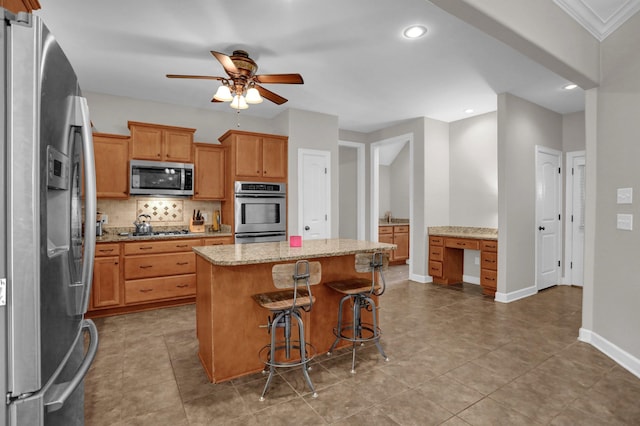 kitchen with baseboards, decorative backsplash, built in study area, a kitchen island, and stainless steel appliances