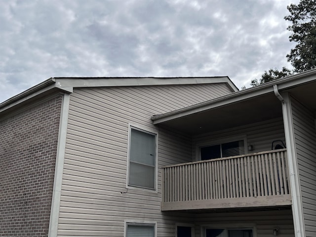 view of property exterior with brick siding and a balcony