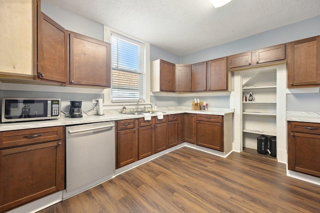 kitchen featuring a textured ceiling, dark wood-type flooring, a sink, light countertops, and appliances with stainless steel finishes