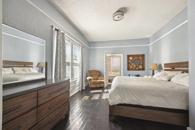 bedroom featuring dark wood-style flooring, a textured ceiling, and baseboards