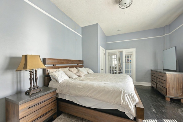 bedroom with a textured ceiling, dark wood-style flooring, and baseboards