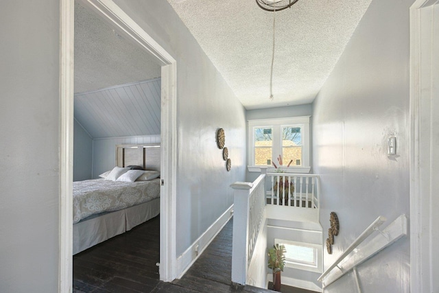 interior space with a textured ceiling, wood-type flooring, an upstairs landing, and baseboards