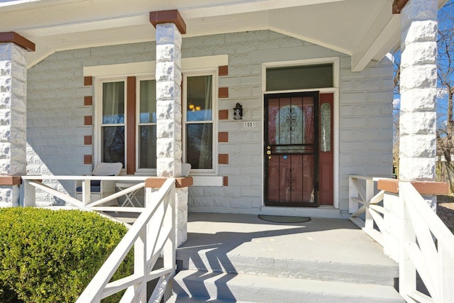 doorway to property with stone siding and covered porch