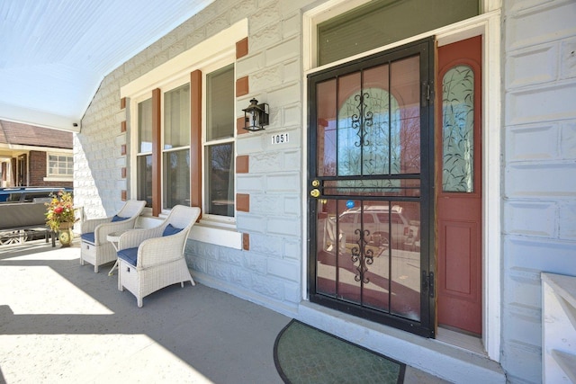 doorway to property featuring a porch, stone siding, and a garage