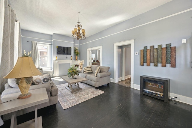 living room featuring a textured ceiling, baseboards, a chandelier, and wood finished floors