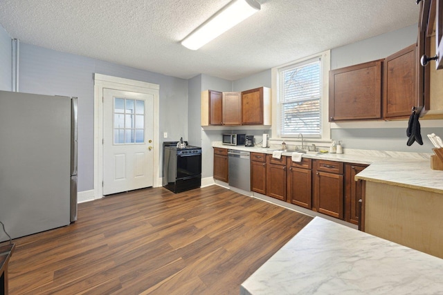 kitchen featuring stainless steel appliances, dark wood-type flooring, a sink, and a textured ceiling